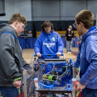 Three students move their robot to the field
